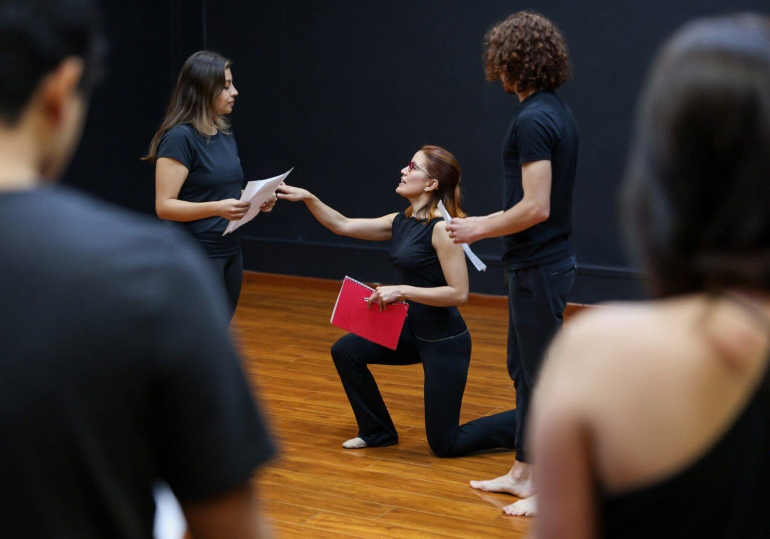 Actors rehearsing on stage with scripts