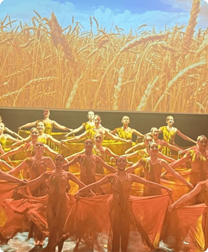 Dancers performing in front of wheat field backdrop