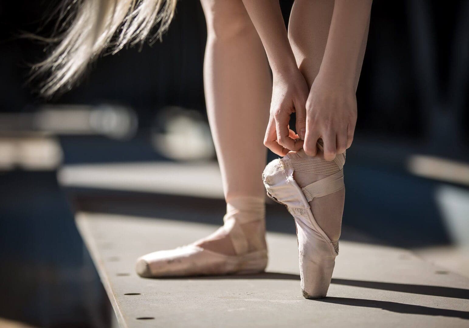 Dancer fixing pink pointe shoes.
