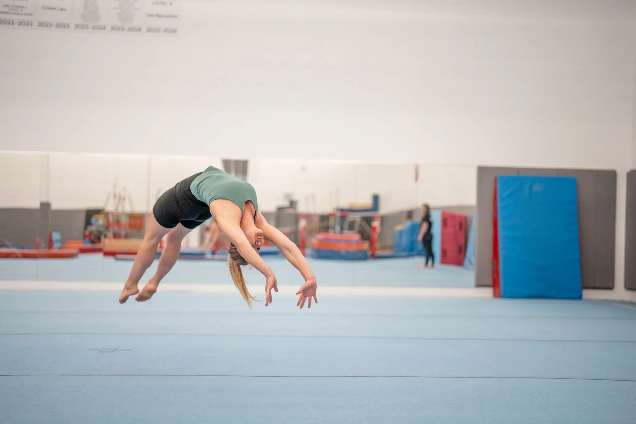 Gymnast performing a mid-air backflip in a gym.